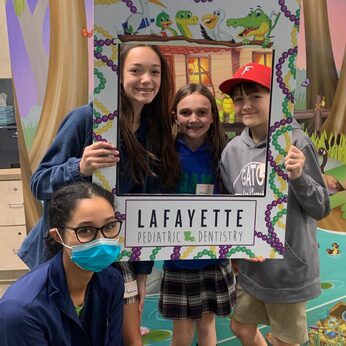 three children holding a selfie frame with a Lafayette Pediatric Dentistry staff member