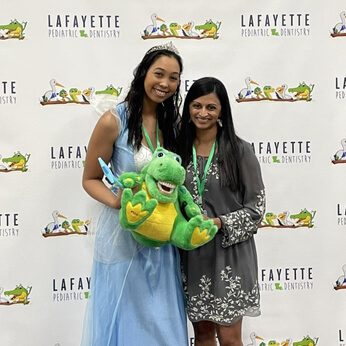 Dr. Gouri with the tooth fairy holding a stuffed animal and looking at the camera