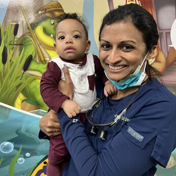 Dr. Gouri holding a toddler and smiling at the camera